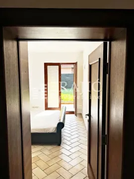 View from the hallway into a bedroom with a bed and courtyard access. - image 13