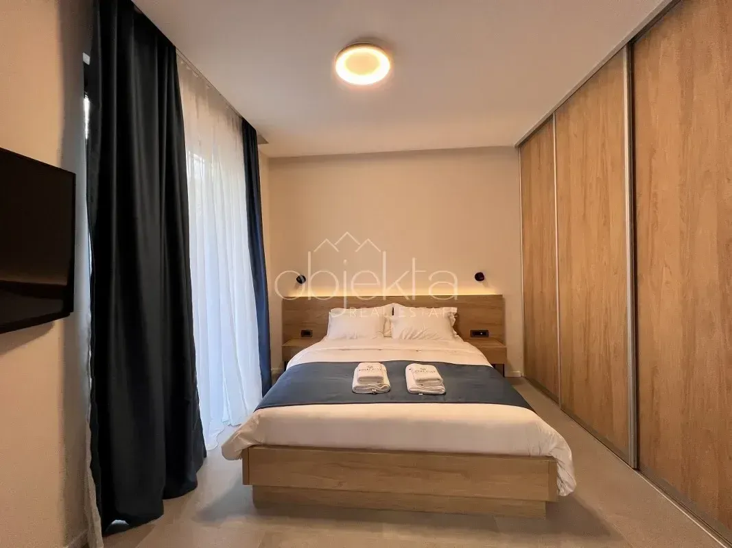 Modern bedroom with a double bed, fitted wardrobe, and balcony doors.