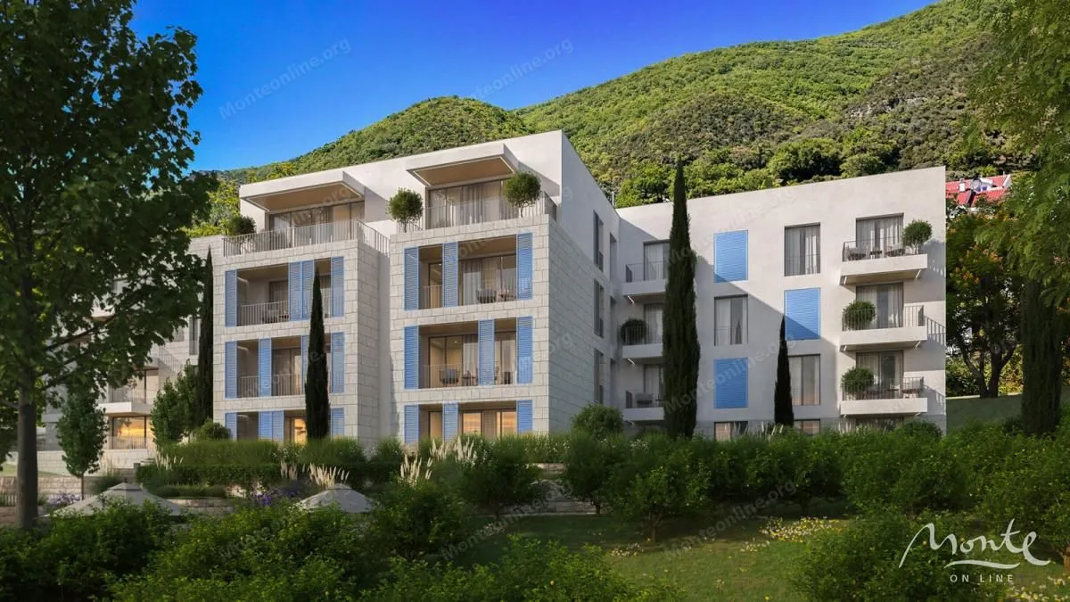 Spoljašnji izgled moderne stambene zgrade okružene zelenilom i brdima.