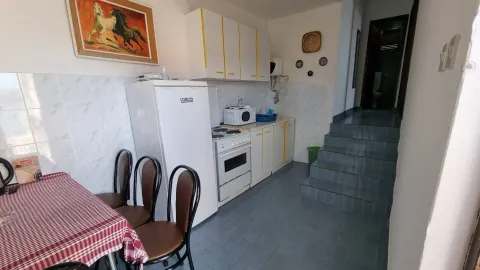 Manja kuhinja sa bijelim elementima, frižiderom i trpezarijskim stolom, pored stepeništa. - image 10