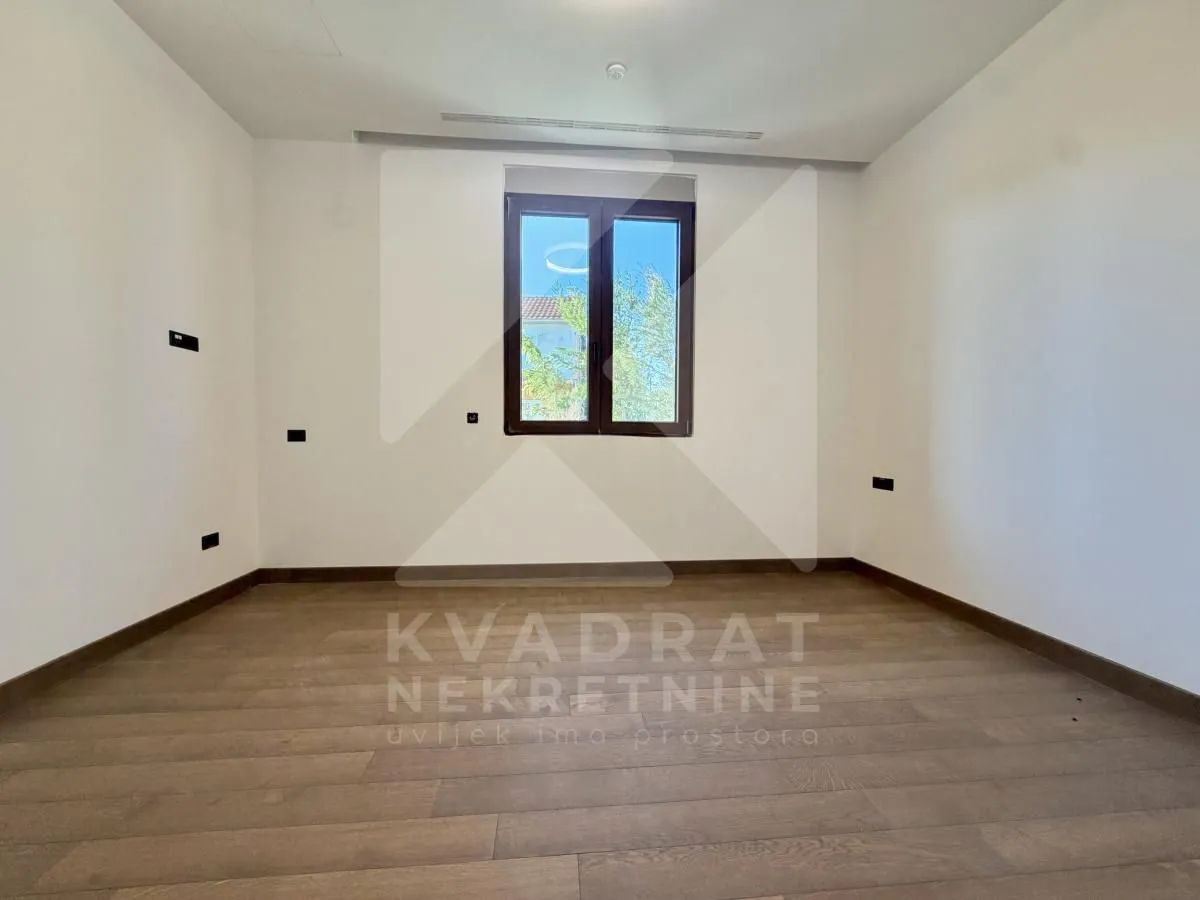 Empty room with hardwood flooring and a single window.