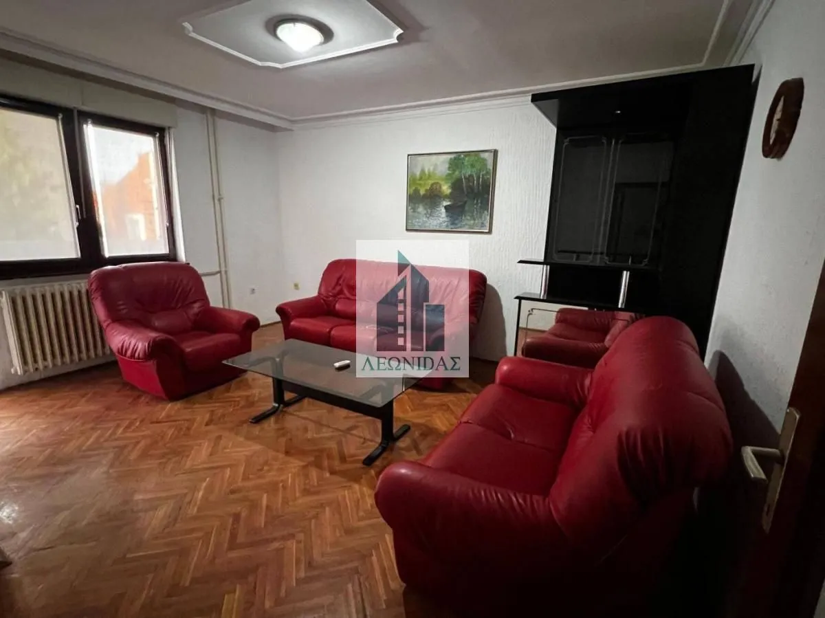 Living room with a red leather sofa set and wooden parquet flooring.