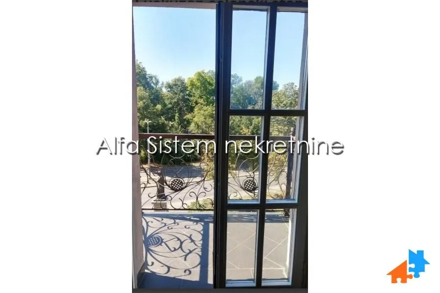 View through the balcony door onto the terrace and green surroundings.