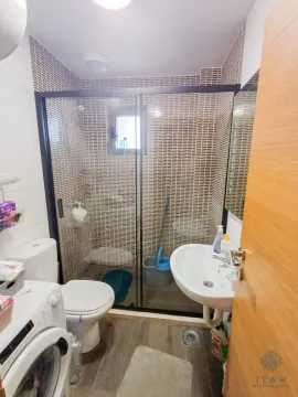 Bathroom with a shower enclosure, washbasin, toilet, and washing machine. - image 8
