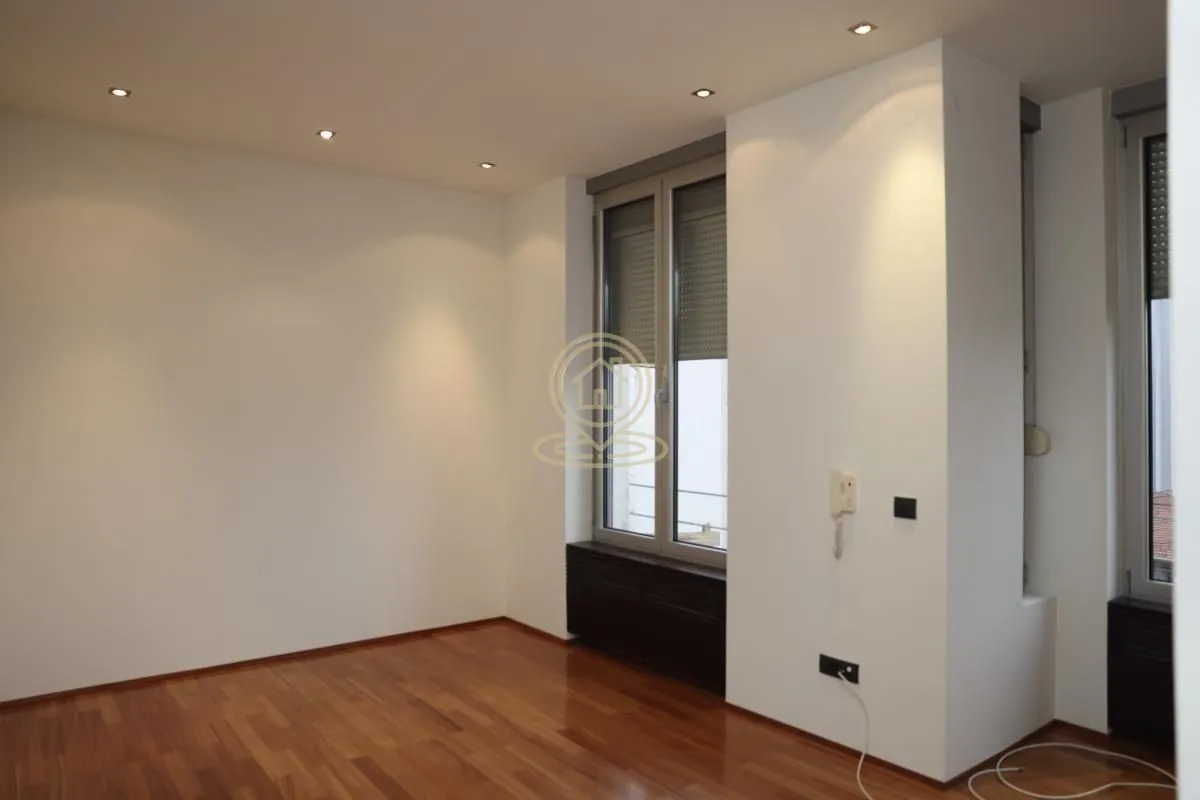 Empty room with hardwood floors and windows.