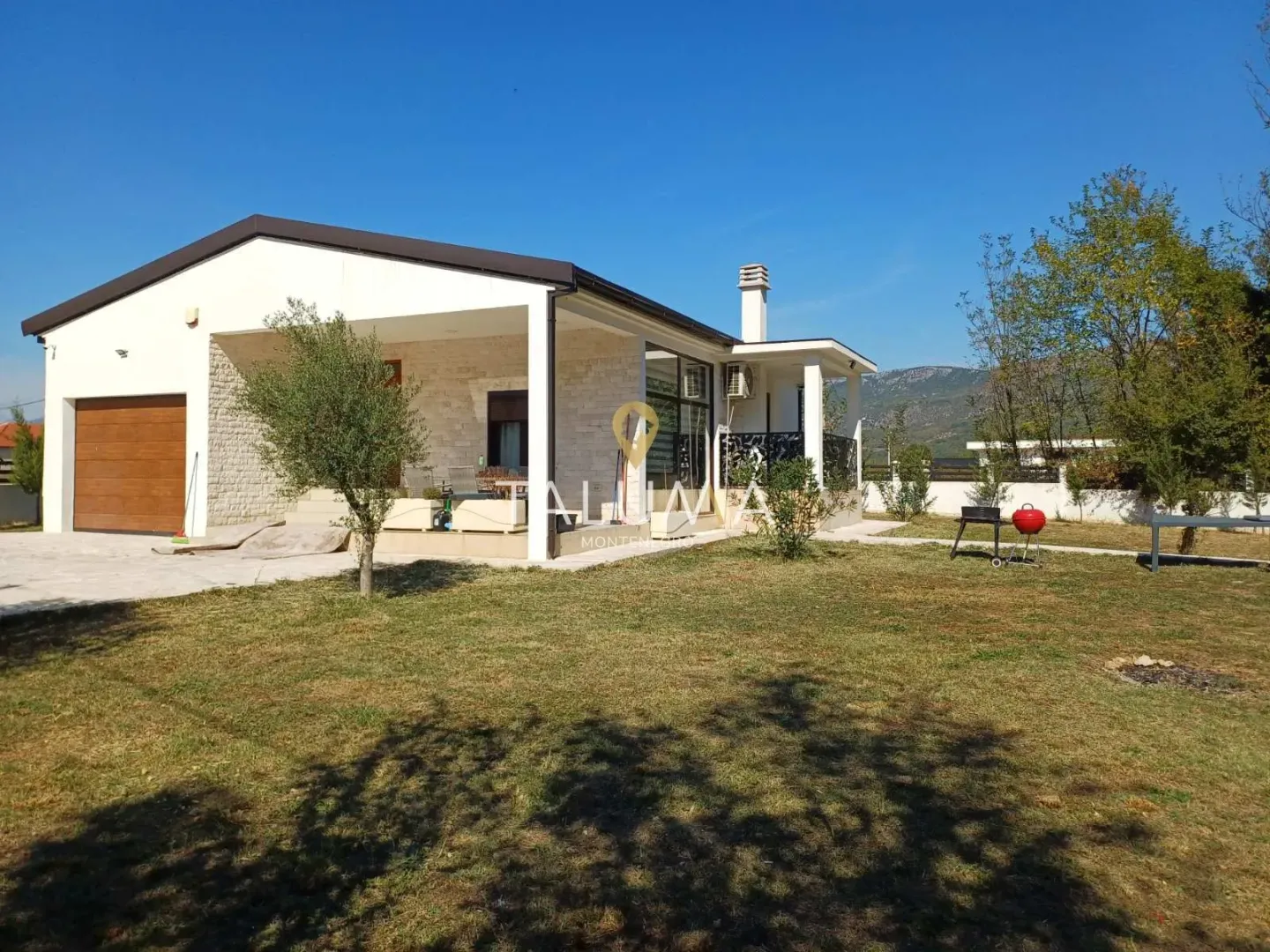 Exterior view of a single-story house with a landscaped yard and terrace.