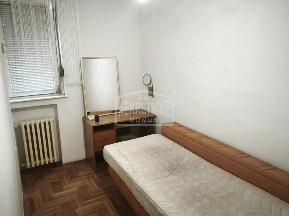 Manja spavaća soba sa krevetom i radnim stočićem sa ogledalom.