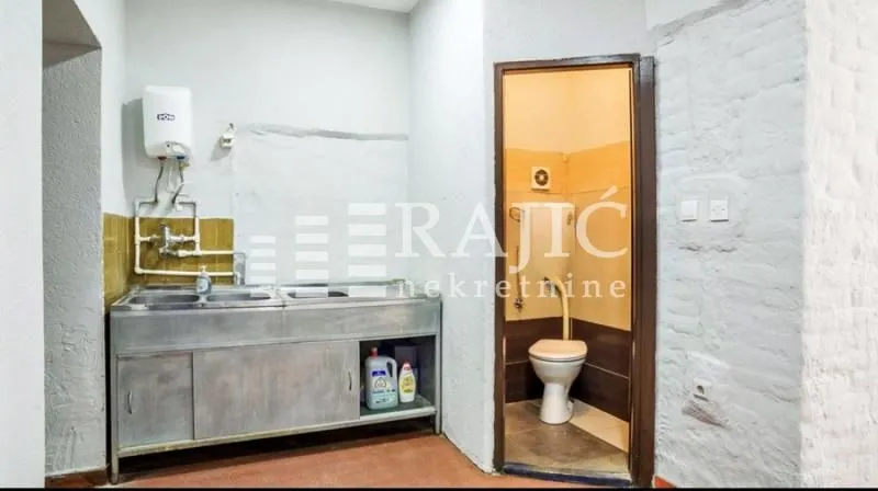 Auxiliary kitchen with a sink and boiler and a view of the bathroom.