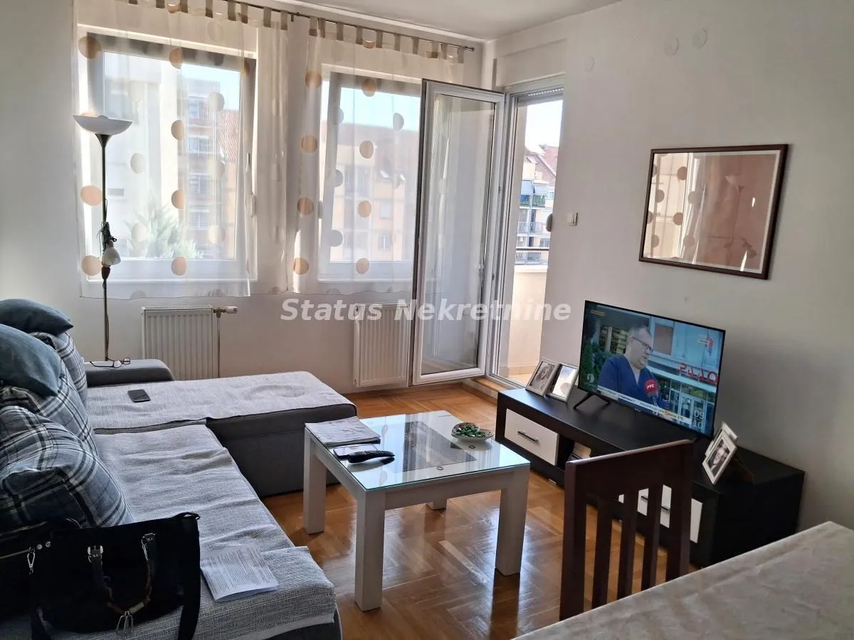 Dnevna soba sa garniturom, stočićem i televizorom.