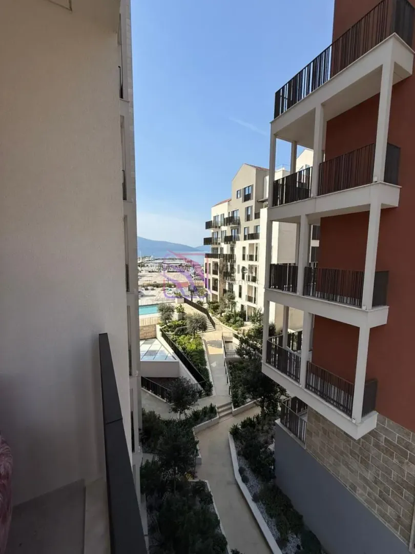 Pogled sa terase na uređeno dvorište zgrade i okolne objekte.