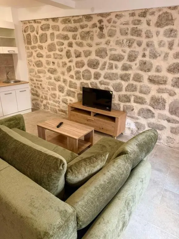 Living room with a green sofa and a stone wall.