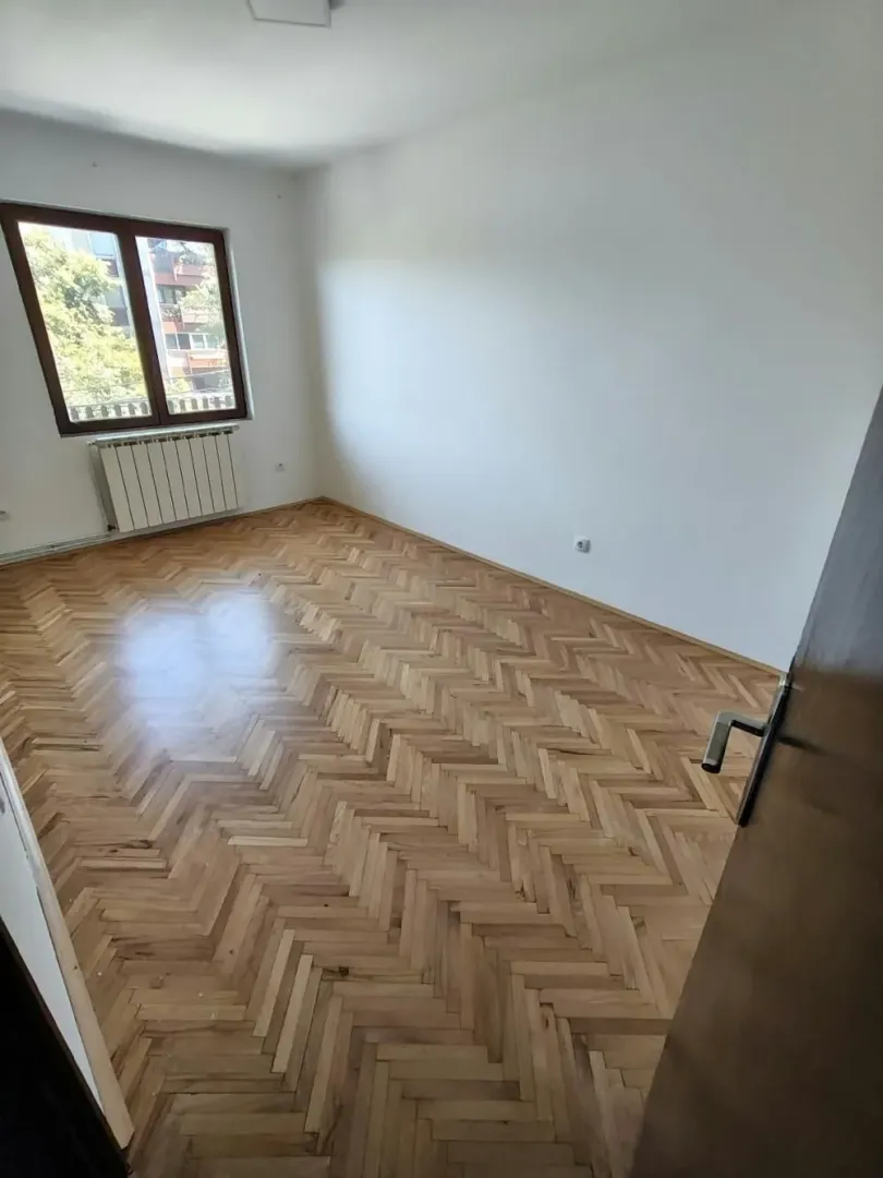 Prazna soba sa parketom i prozorom.