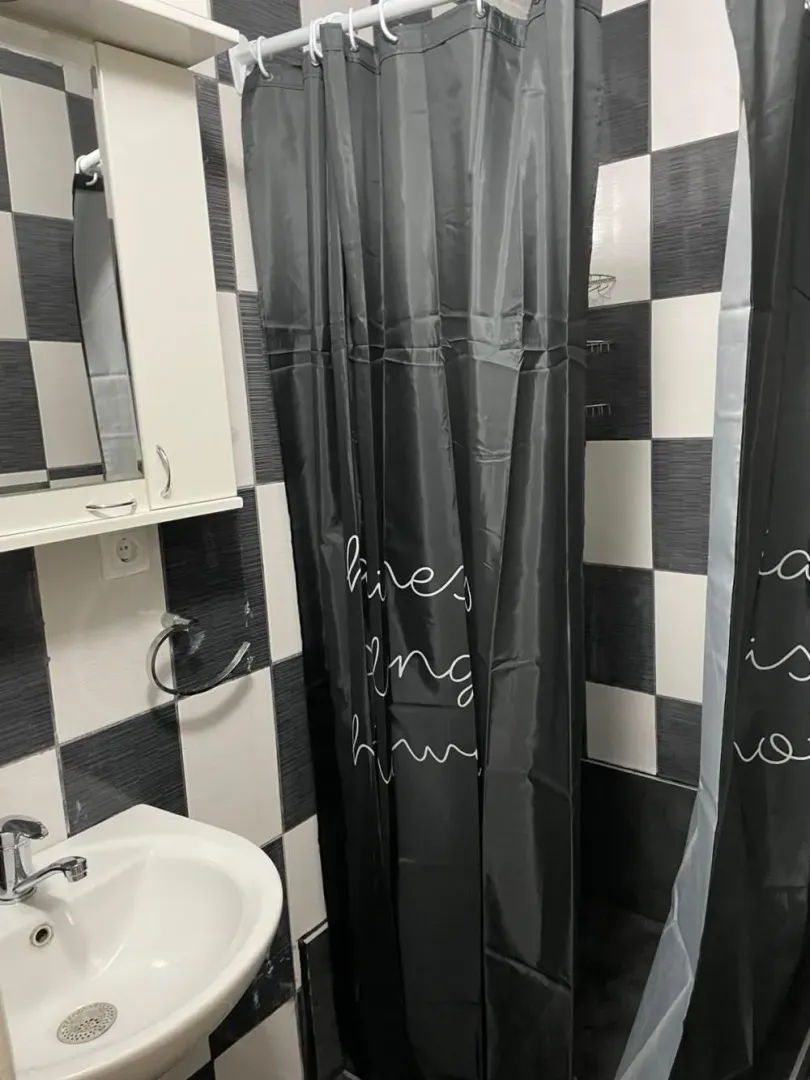 Bathroom with a sink, mirror, and a shower stall with a black curtain.
