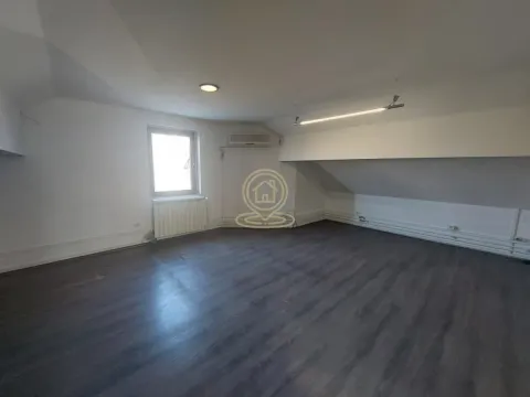 Empty attic room with dark flooring and a window. - image 2