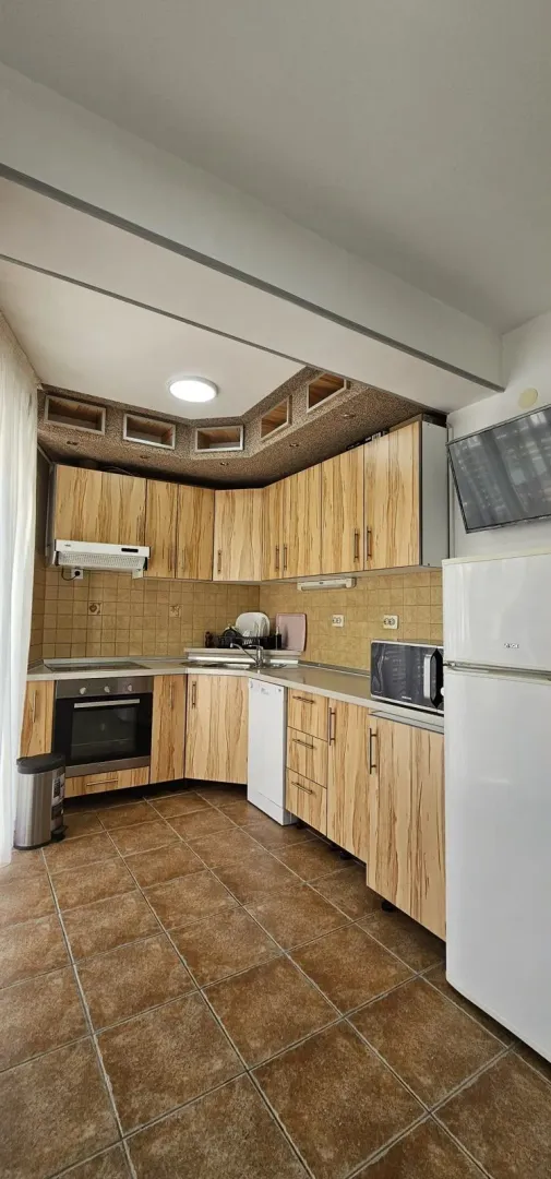 Fully equipped kitchen with wooden cabinetry and white goods.