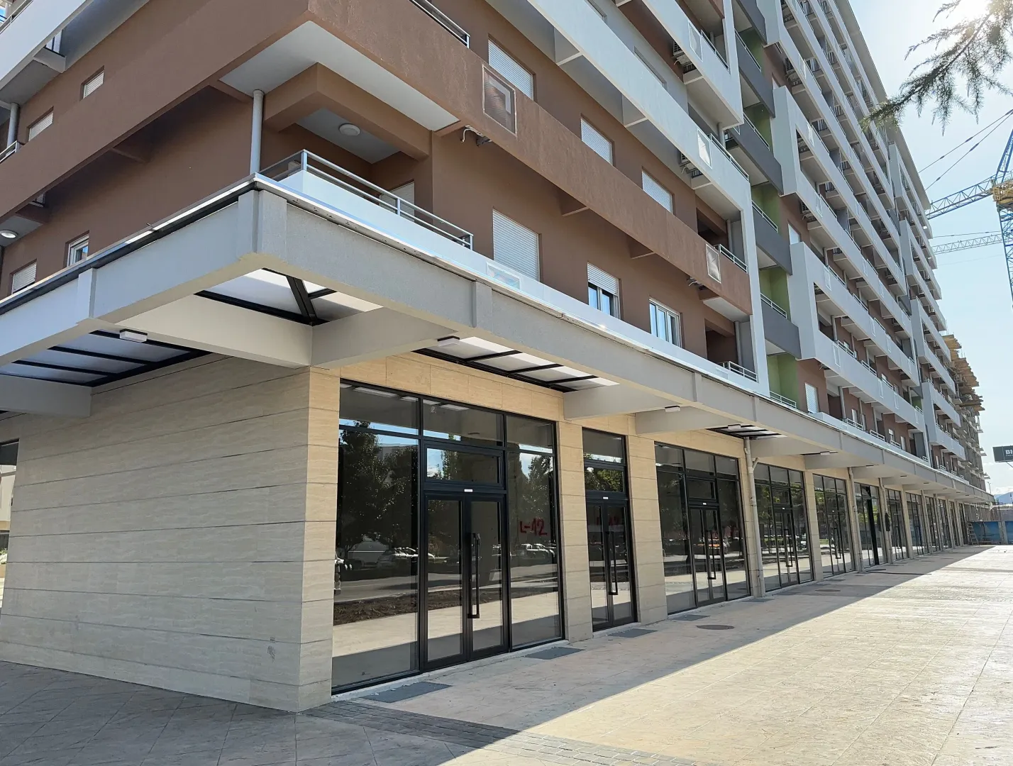 Exterior of a modern multi-story residential and commercial building with ground floor retail spaces.