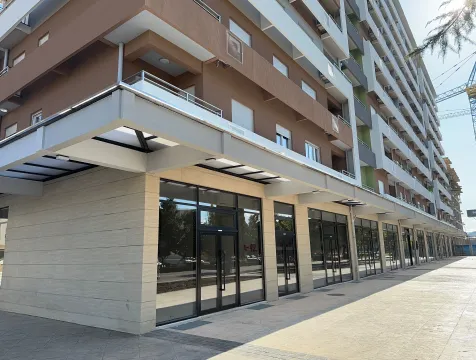 Exterior of a modern multi-story residential and commercial building with ground floor retail spaces. - image 7