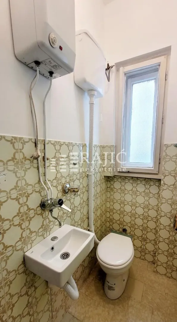 Small bathroom with a sink, toilet, and wall-mounted water heater.