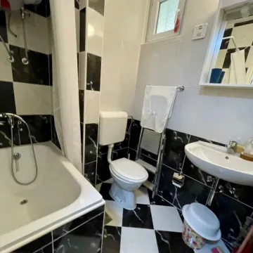 Kompaktno kupatilo sa kadom, umivaonikom i crno-bijelim pločicama. - image 3