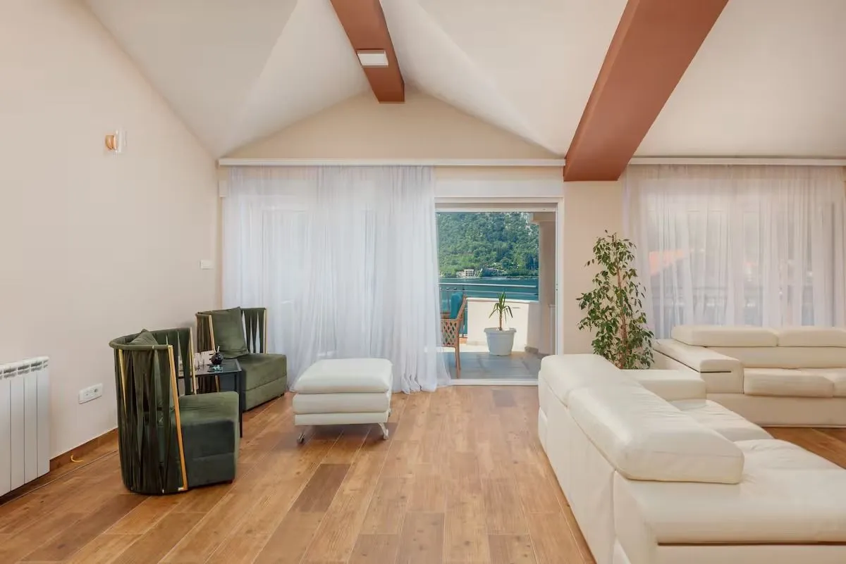 Spacious living room with seating area, high ceiling, and access to the terrace.