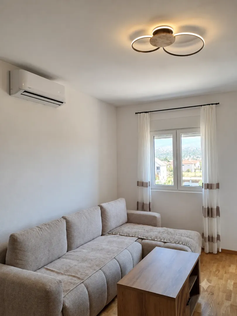 Living room with a sectional sofa, coffee table, and air conditioning.