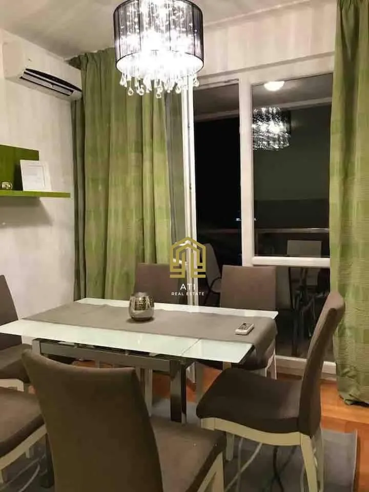 Trpezarija sa stolom, stolicama i lusterom.