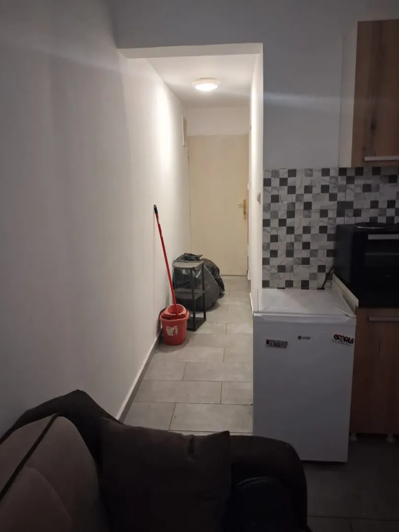 Small kitchen area with a hallway section and cleaning supplies.