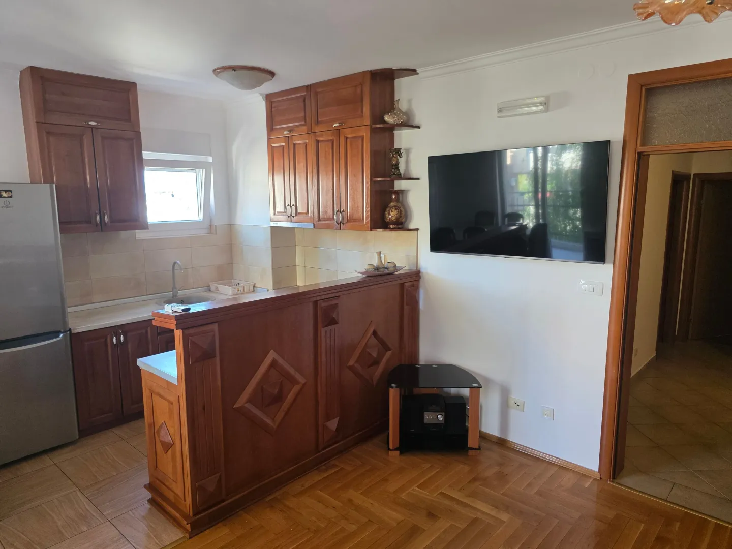 Equipped kitchen with wooden elements and a bar counter connected to the living area.