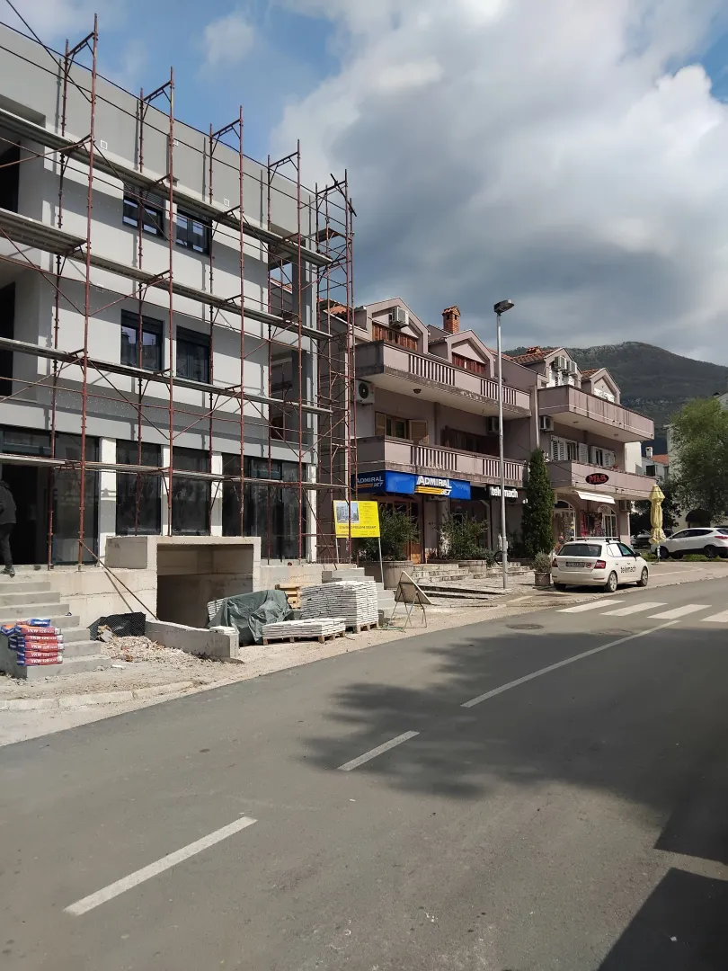 Street view of a building under construction with scaffolding and neighboring properties.
