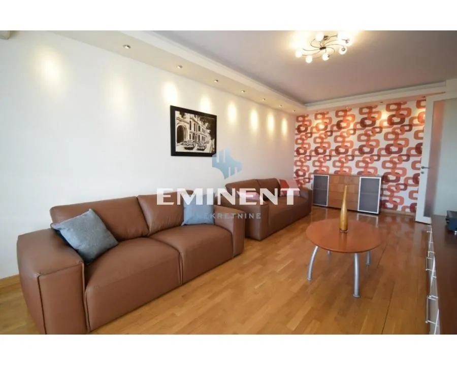 Living room with leather sofa set and parquet flooring.