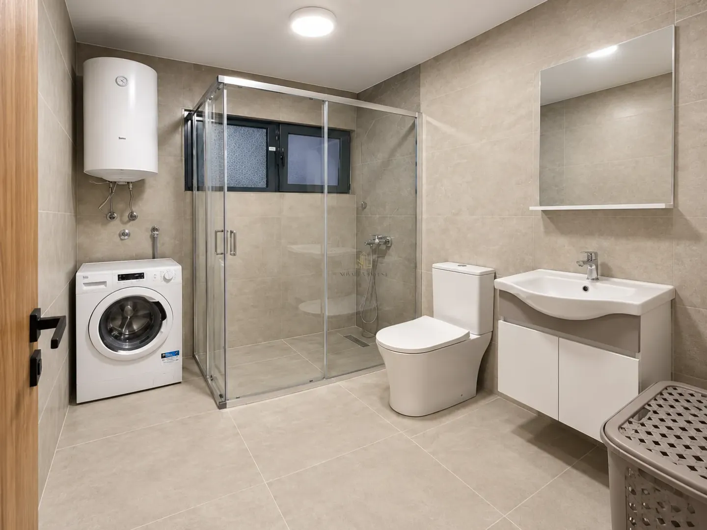 A modern bathroom equipped with a walk-in shower, washbasin, toilet, and washing machine.