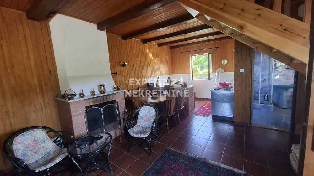 Living room with a fireplace, dining area, and wooden wall paneling.