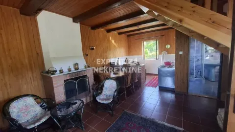 Living room with a fireplace, dining area, and wooden wall paneling. - image 6