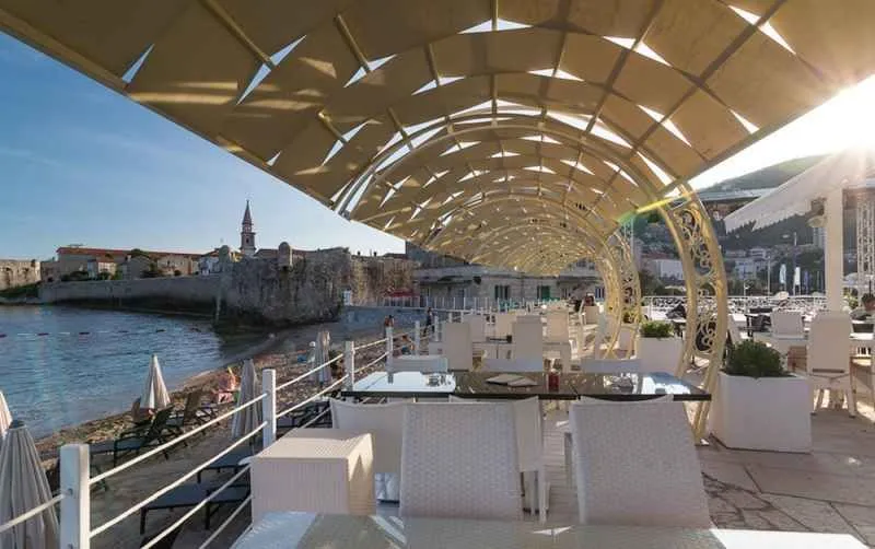 Natkrivena terasa restorana sa pogledom na more i obalu.