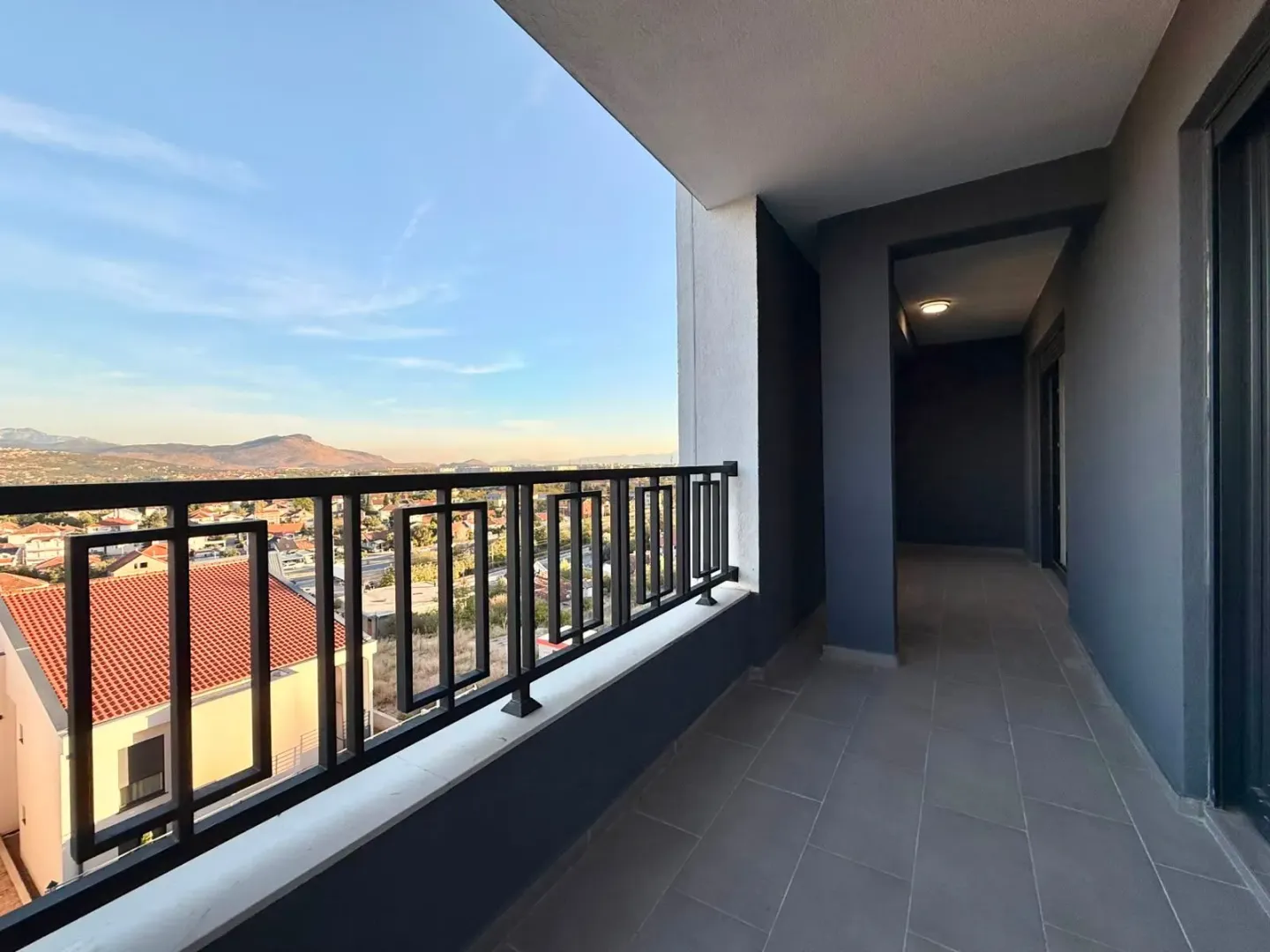 Prostrana pokrivena terasa sa pogledom na grad i okolna brda.