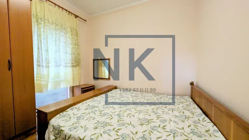 Furnished bedroom with a double bed, wooden wardrobe, and a window.