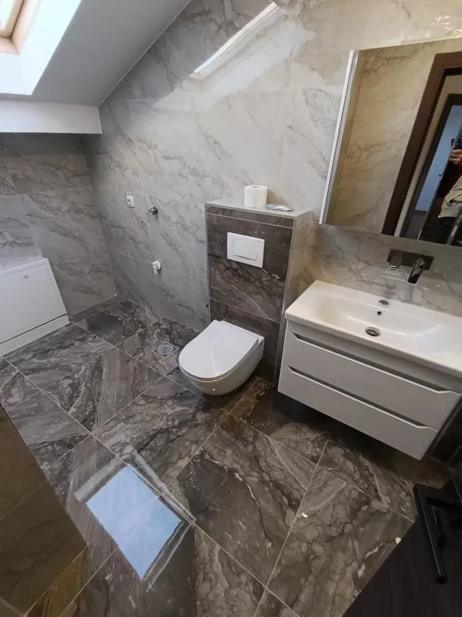 Moderno kupatilo obloženo keramičkim pločicama sa ugradnim toaletom i umivaonikom.