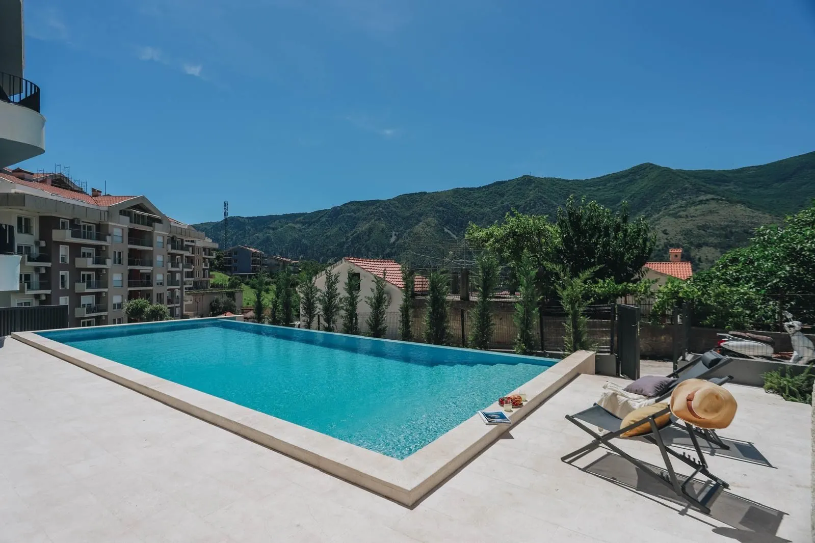 Swimming pool with sun loungers and mountain view.