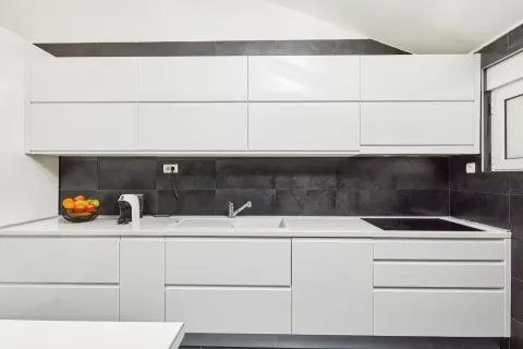 Modern kitchen with white units and dark tiles. - image 9
