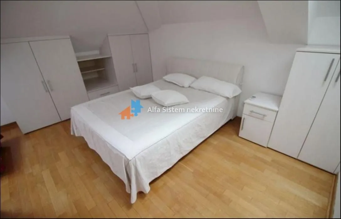 Furnished bedroom with a double bed and built-in wardrobes under a sloping ceiling.