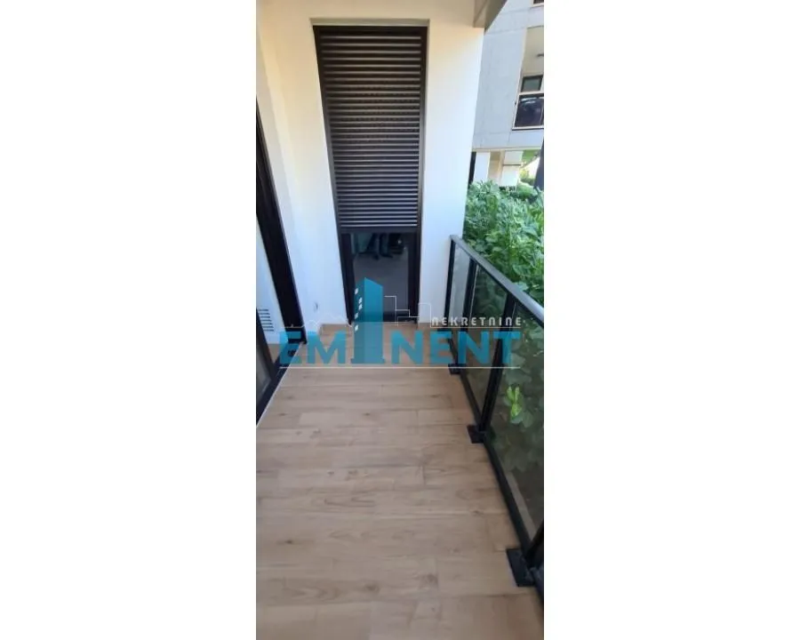 Pogled na prostrani balkon sa drvenim podom i zaštitnom ogradom.