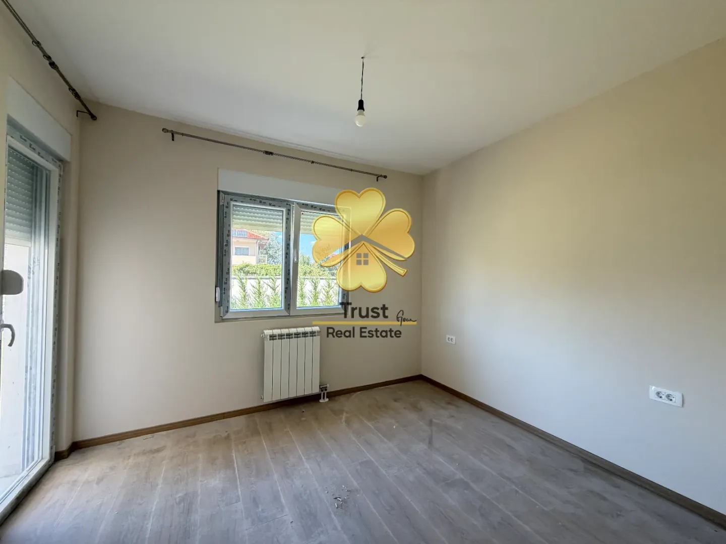 Empty room with a window and wooden flooring.