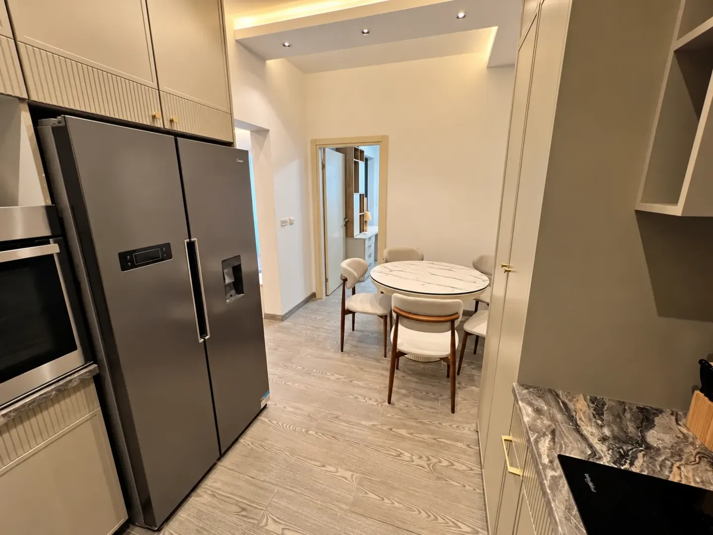 Modern kitchen with a large refrigerator and a dining table with chairs.