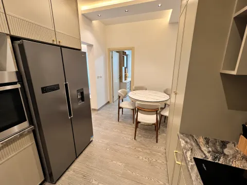 Modern kitchen with a large refrigerator and a dining table with chairs. - image 13