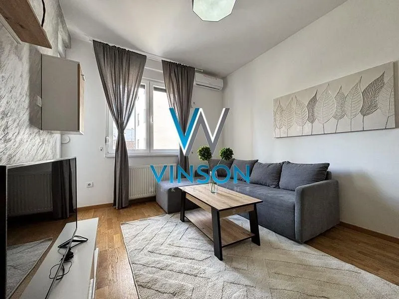 Living room with a sofa, coffee table, and television.