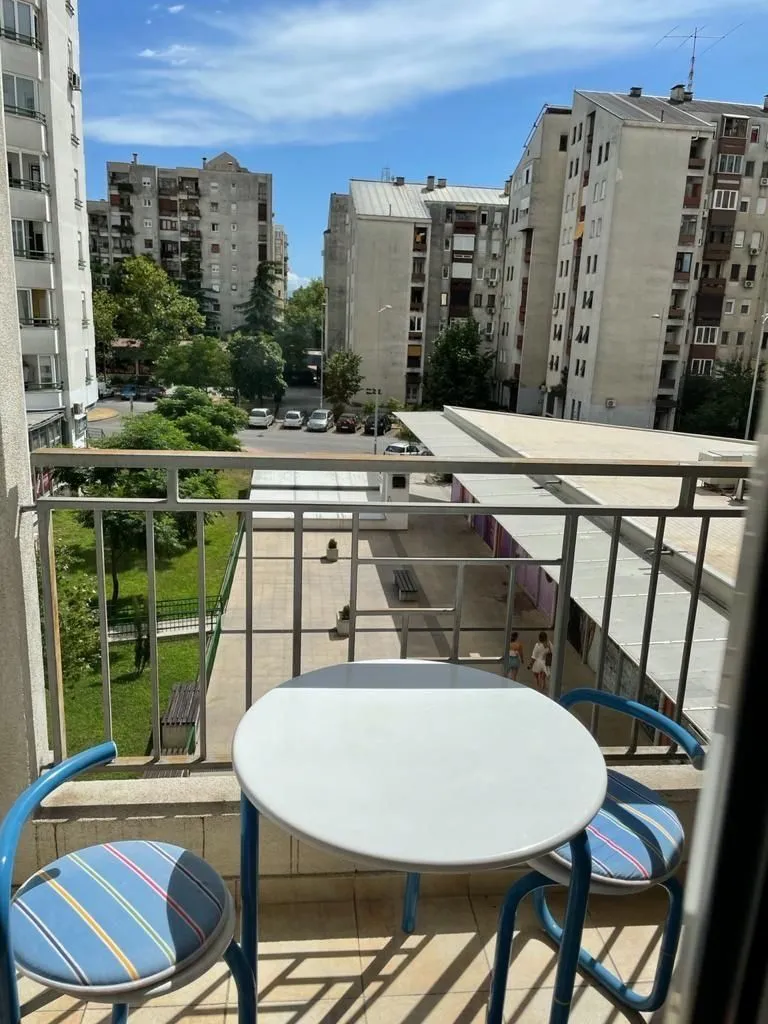 Small table and chairs on a balcony with a neighborhood view.