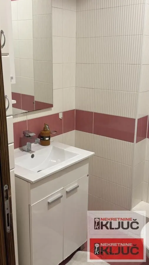 Manje kupatilo sa umivaonikom, ormarićem i ogledalom.