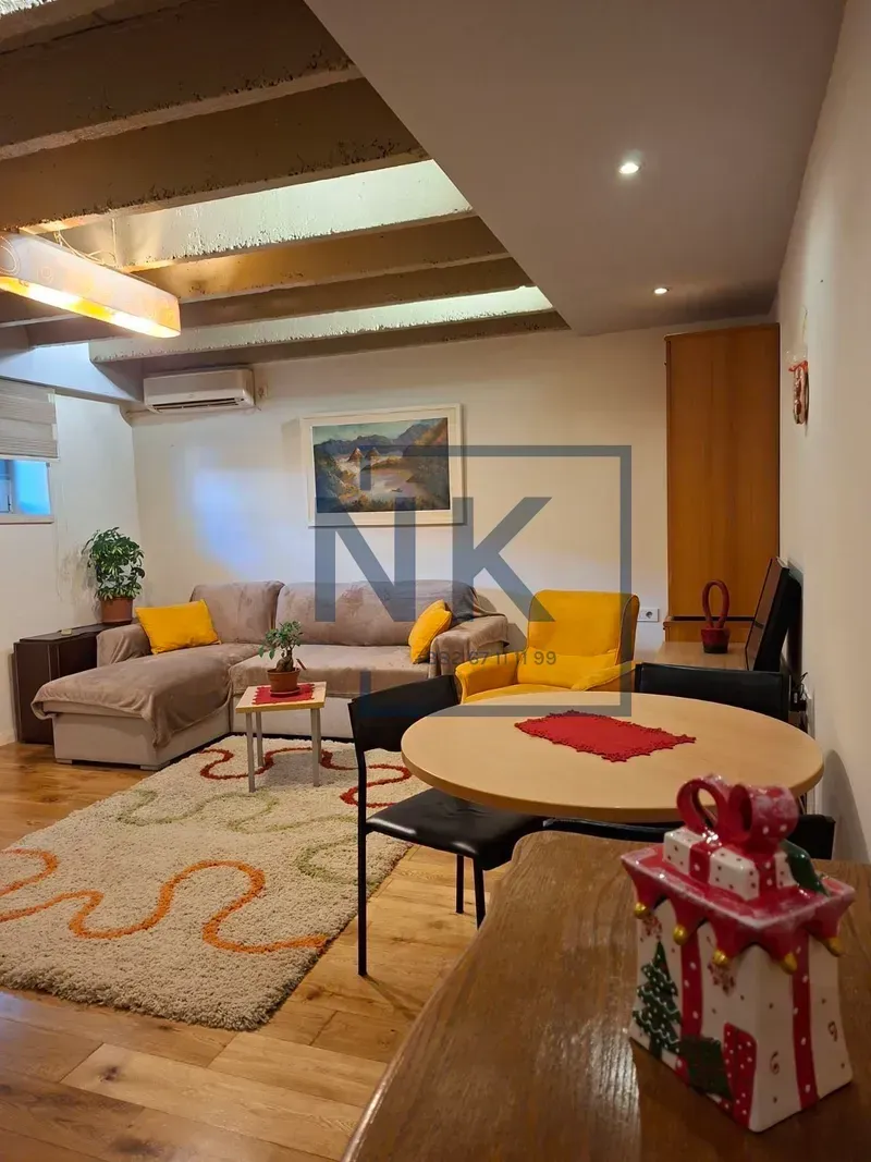 Living room with sofa, dining table, and decorative ceiling beams.