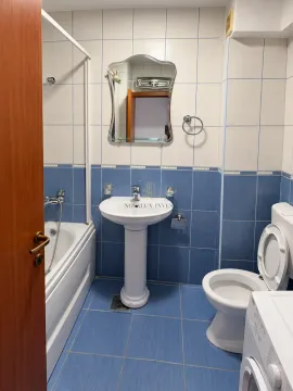 Bathroom equipped with a bathtub, washbasin, toilet, and a mirror. - image 7