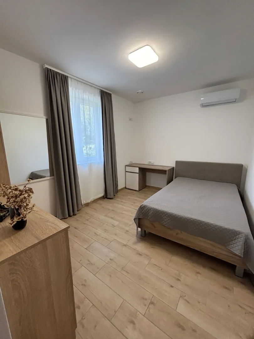 Namještena spavaća soba sa bračnim krevetom, radnim stolom i prozorom.